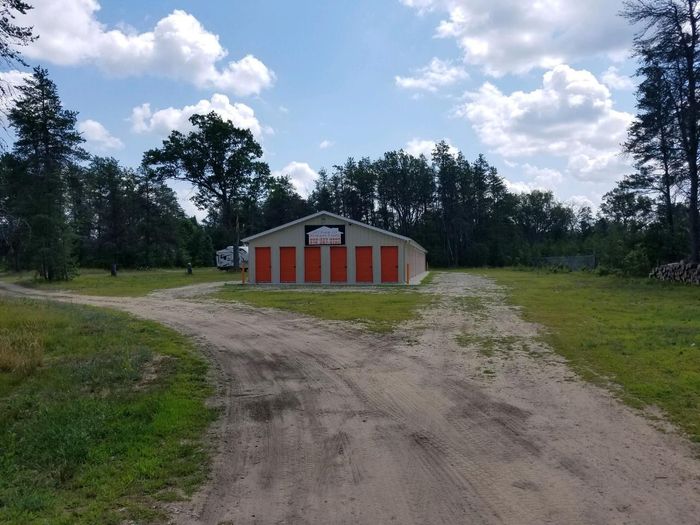 Gravel drive leading through grass to a storage building in summer