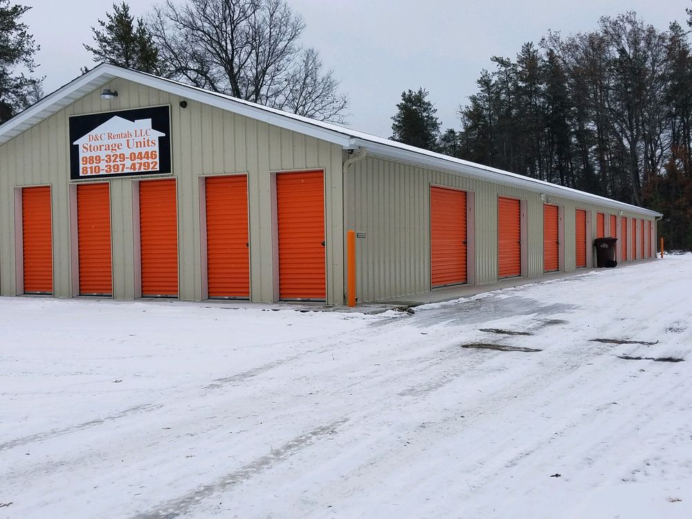 D&C Rentals storage building in winter with its sign listing the phone numbers above the orange doors